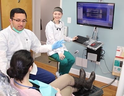 Dentist team member and patient looking at dental images on computer