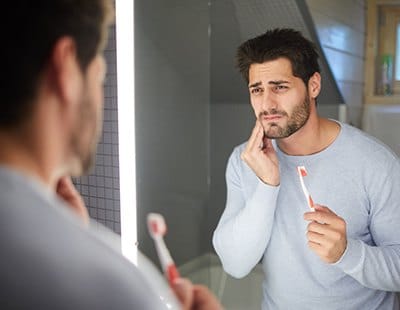 Man in need of emergency dentistry holding jaw