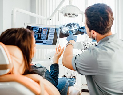 a dentist showing a patient her X-ray and diagnostic images