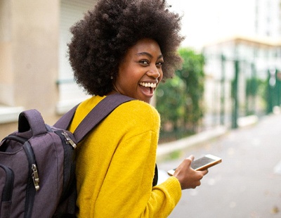 a smiling person with their phone in their hand looking over their shoulder