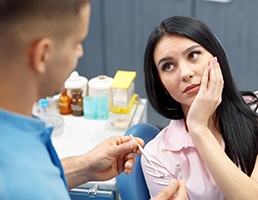 Woman at dentist’s office holding her face in pain