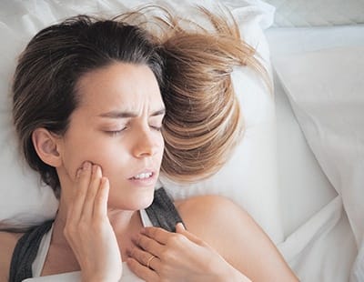 Woman in need of tooth extraction holding cheek in pain