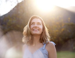 Woman smiling outside with dental implants in Ellicott City