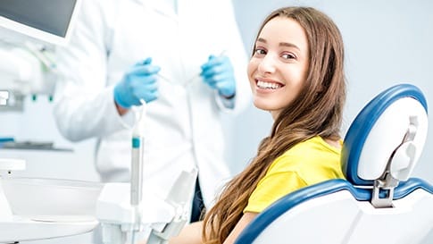 Woman in dental chair smiling over her shoulder
