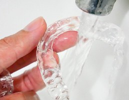 Patient in Ellicott City cleaning their Invisalign aligner