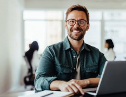 Man with glasses smiling while working