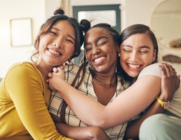 Group of friends smiling and hugging while sitting on couch