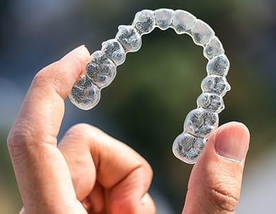 Hand holding an Invisalign tray