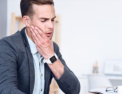 Man in need of T M J treatment holding jaw