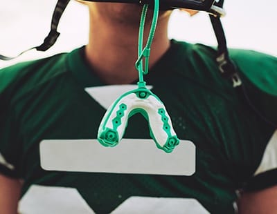 Greent athletic mouthguard hanging from helmet