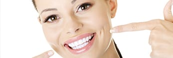 Woman pointing to her beautiful smile after cosmetic dentistry
