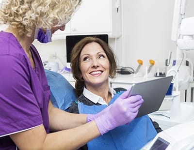 Dental team member and patient looking at digital x-rays